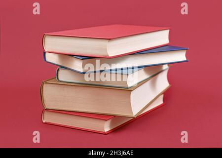 Stack of old hardcover books on dark red background Stock Photo