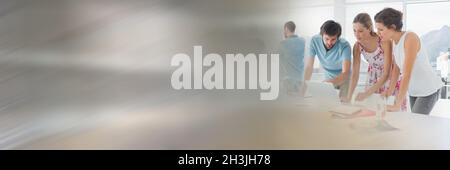 Male and female professionals discussing over laptop while leaning on conference table at board room Stock Photo