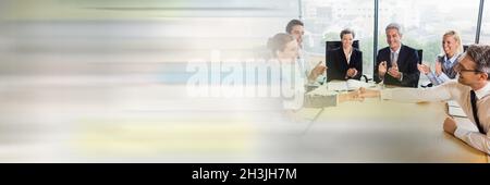Smiling businessman shaking hands with businesswoman while colleagues applauding in office Stock Photo