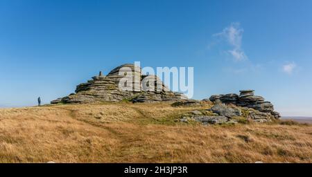 Walker approaching Great LInks Tor with its prominent Trig Point on Western Dartmoor in Devon UK Stock Photo