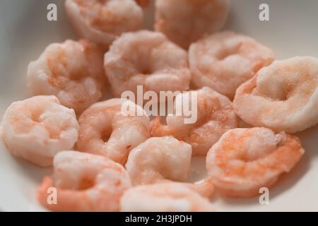 Frozen pre cooked shrimps in white bowl, shallow focus Stock Photo