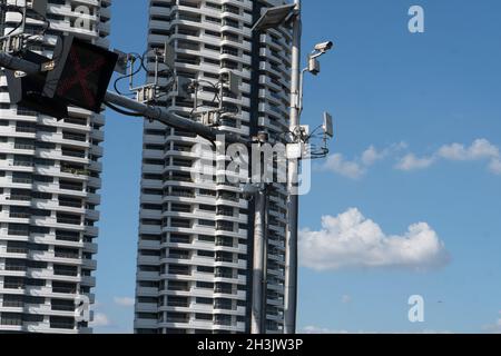 Closeup shot of street light on red and CCTV camera over tall buildings Stock Photo