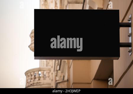 Mock up. Blank black rectangular shape signboard on the wall outdoors. Signage of shop, store, cafe, restaurant Stock Photo