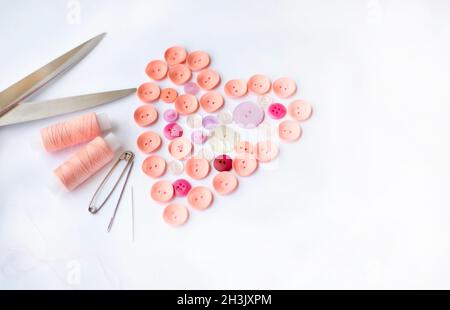 Sewing accessories. Button heart shape. Spools of thread. Tailor's scissors. Tailor's pins and needles. Copy space for text. Stock Photo
