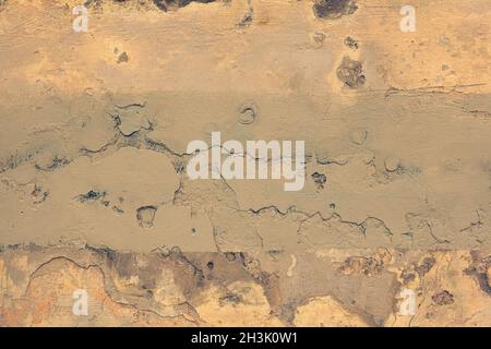 Old cracked weathered shabby yellow painted plastered peeled wall background. Chipped broken uneven rough stucco wall texture wallpaper Stock Photo