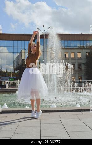 Love story of stylish funny couple: young man in a t-shirt. And a cute young woman in wedding white skirt and yellow sweater. Family holiday, date Stock Photo