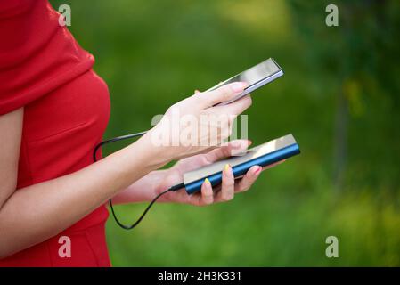 Young woman charging smartphone using a power bank. Stock Photo