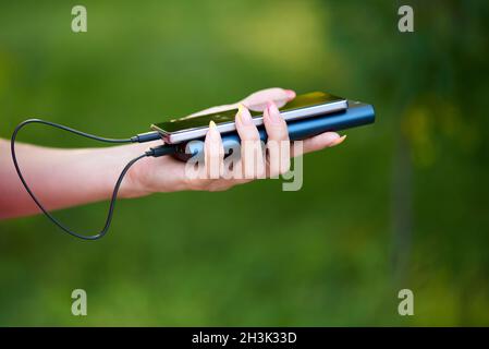 Smartphone and power bank in the hands of a young woman. Stock Photo