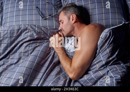 Sleeping young man in bed under the duvet. Stock Photo