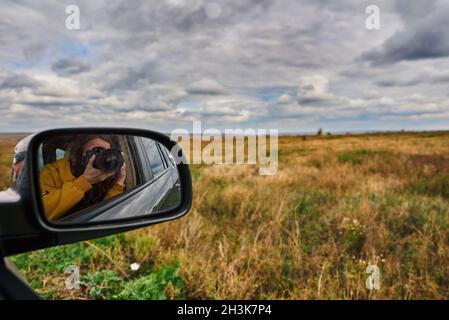 Young woman shoots a landscape on a road trip. Stock Photo