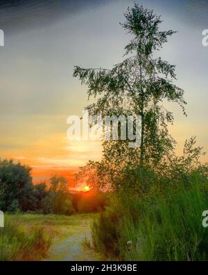 Colorful and dramatic sky during sunset over a rural countryside area Stock Photo