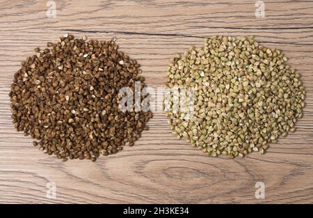 Pile of buckwheat and green buckwheat on wooden background. Stock Photo