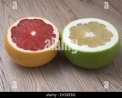 Halves of Green Sweetie and Red Grapefruit on wooden background. Close up view. Stock Photo