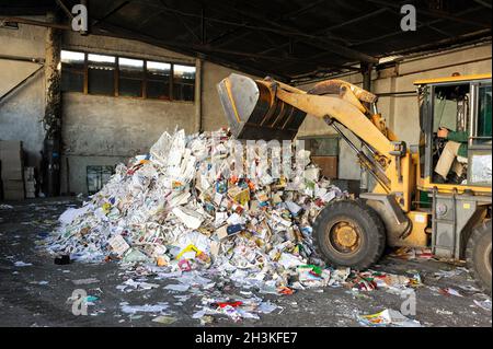 Excavator dumps cardboard garbage at waste recycling plant Stock Photo