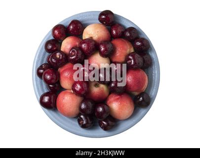 Sweet cherries and ripe juicy nectarines in a dish, on white background. Healthy food with vitamins. Stock Photo