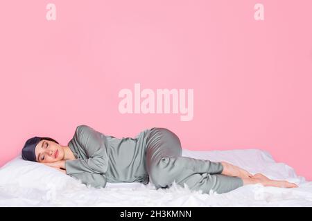 Photo of shiny adorable young lady sleepwear smiling lying blanket closed eyes isolated pastel pink color background Stock Photo
