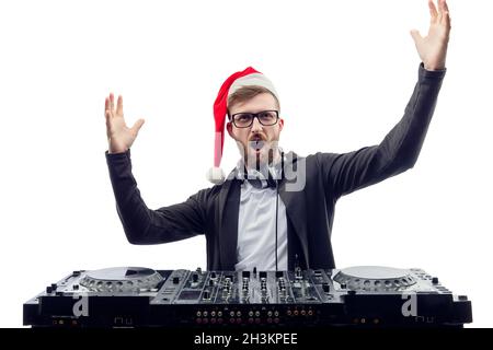 Funny screaming guy dj in Santa's hat, glasses plays music on a turntable raises hands up. studio shot  Stock Photo