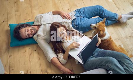 A Lovely Couple Lying on the Floor Using a Laptop, spouses enjoying of Each Other. Stock Photo