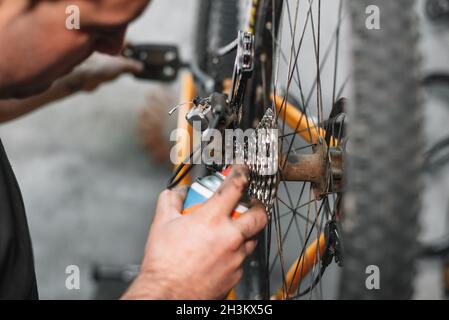Mechanic man Hands, Spraying Oil To A Bike Chain. Bicycle maintenance. Stock Photo