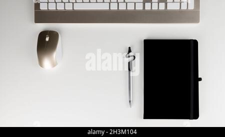 Stock photography of stylized white office table with blank notepad and pen and keyboard and mouse Stock Photo