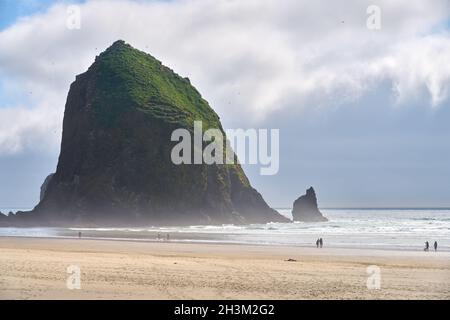 Haystack Rock Cannon Beach Afternoon. Sunrise at Haystack Rock in Cannon Beach, Oregon as the surf washes up onto the beach. United States. Stock Photo