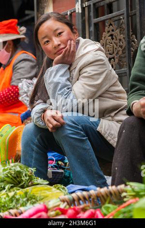 Tibetan girl / ethnic women of Tibet, resident or local to the walled ancient Chinese town (ancient walled city) of Songpan in northern Sichuan, China. Selling salad and vegetables at an informal Street vegetable market. (125) Stock Photo