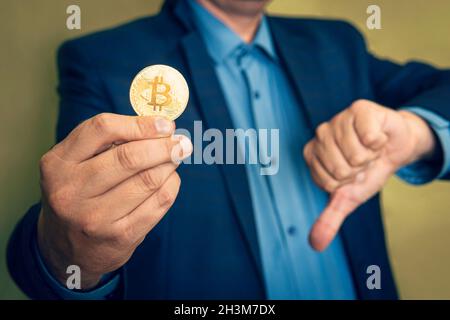 Man holding golden physical bitcoin. Investment risk. Profit and Revenue Drop from Bitcoin Trading and Cryptocurrency Mining Stock Photo