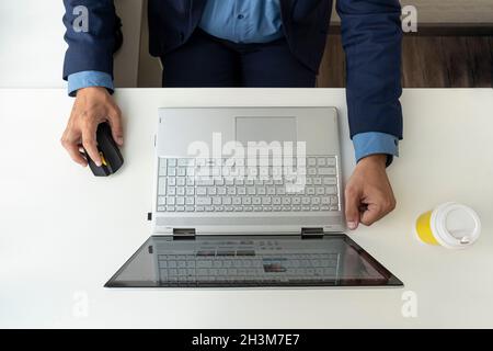 Man working with laptop, top view. businessman at work in the office. a computer on a white desk and the manager's hands in a jacket. Stock Photo