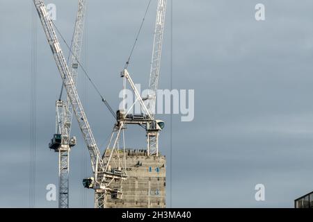 Three tower cranes working on the construction of a tall building in Glasgow city centre. Stock Photo