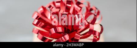 banner of present box in craft paper with red bow on grey background Stock Photo