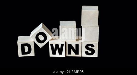 Down text and down arrows are written on wooden blocks and black glass background Stock Photo