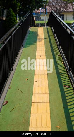 Pedestrian walking on tactile paving on footpath in selective focus Stock Photo