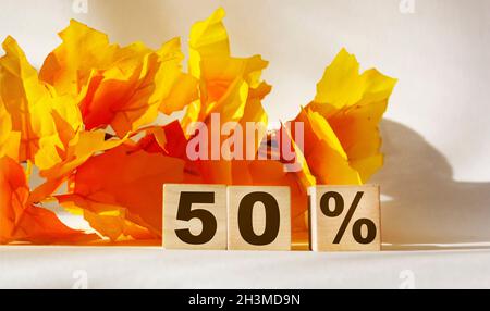 50 percent written on wooden blocks against orange foliage background and white backdrop Stock Photo