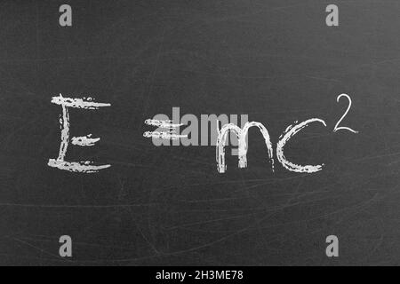Relativity equation E mc2 handwritten by chalk on a university blackboard. Science and education concepts and backgrounds Stock Photo