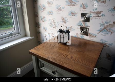 Old fashioned wind up alarm clock on side table in bedroom of pub and hotel The Devonport, in Middle One Row, Darlington, County Durham Stock Photo