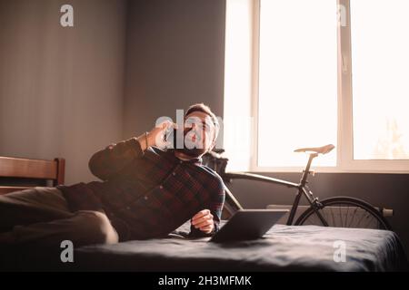 Happy man talking on smart phone lying on bed at home Stock Photo