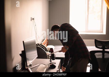 Man holding laptop while standing by desktop computer at home Stock Photo