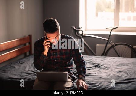 businessman talking on smart phone while using laptop at home Stock Photo