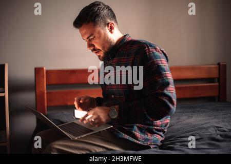 Man using laptop computer and smart phone at home Stock Photo