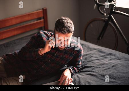 Happy man talking on smart phone while using laptop computer at home Stock Photo