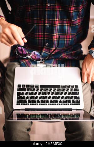 Man holding glasses and laptop computer working at home Stock Photo