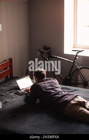 Man using laptop computer lying on bed at home Stock Photo