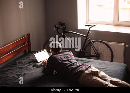 Man using laptop computer lying on bed at home Stock Photo