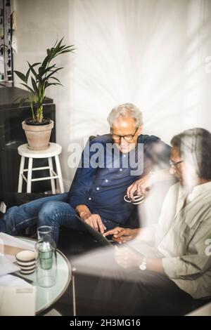 Male and female colleagues working on laptop in retail shop Stock Photo