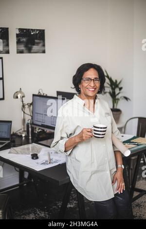 Happy craftswoman with coffee cup at workshop Stock Photo