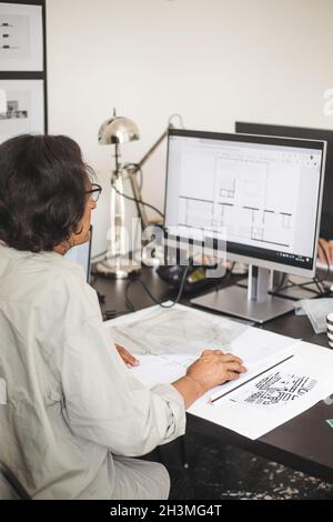 Senior female entrepreneur working on computer at table in office Stock Photo
