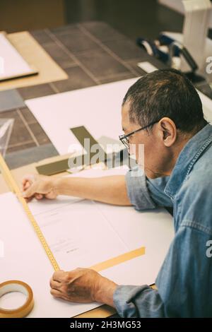 Craftsman measuring paper while working in office Stock Photo