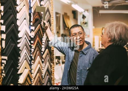 Craftsman showing frames to female customer at workshop Stock Photo