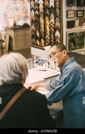 Senior craftsman showing frames to female customer in office Stock Photo