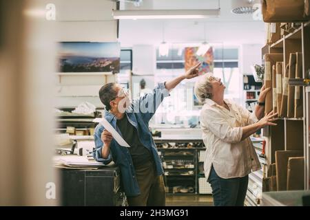 Craftsman pointing while discussing over frames with female coworker at workshop Stock Photo